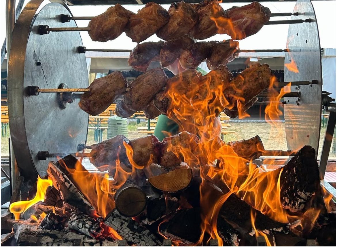 Spiedi di carne che girano sul fuoco a legna