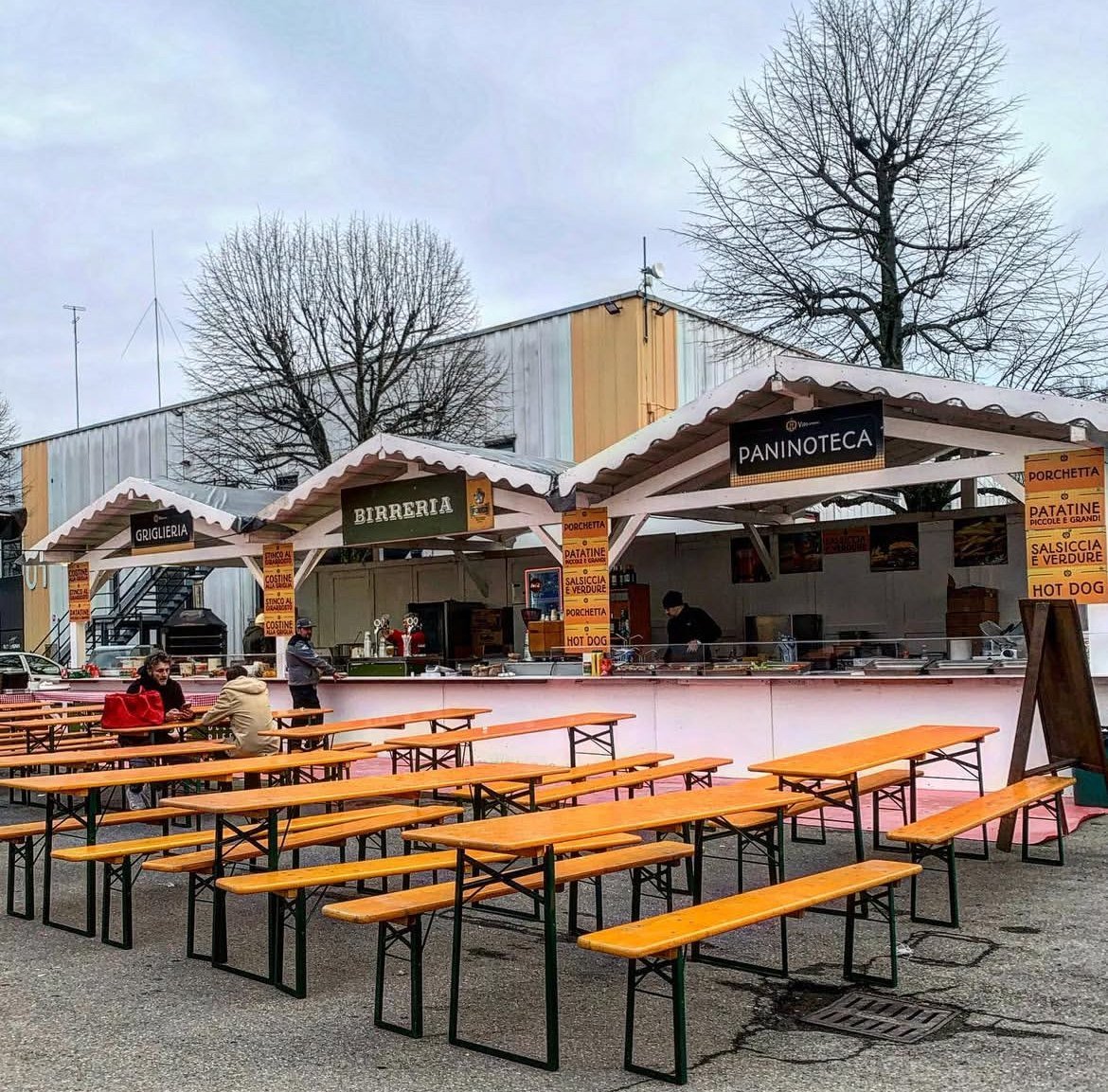 Stand birreria e paninoteca con tavoli in legno a un mercatino